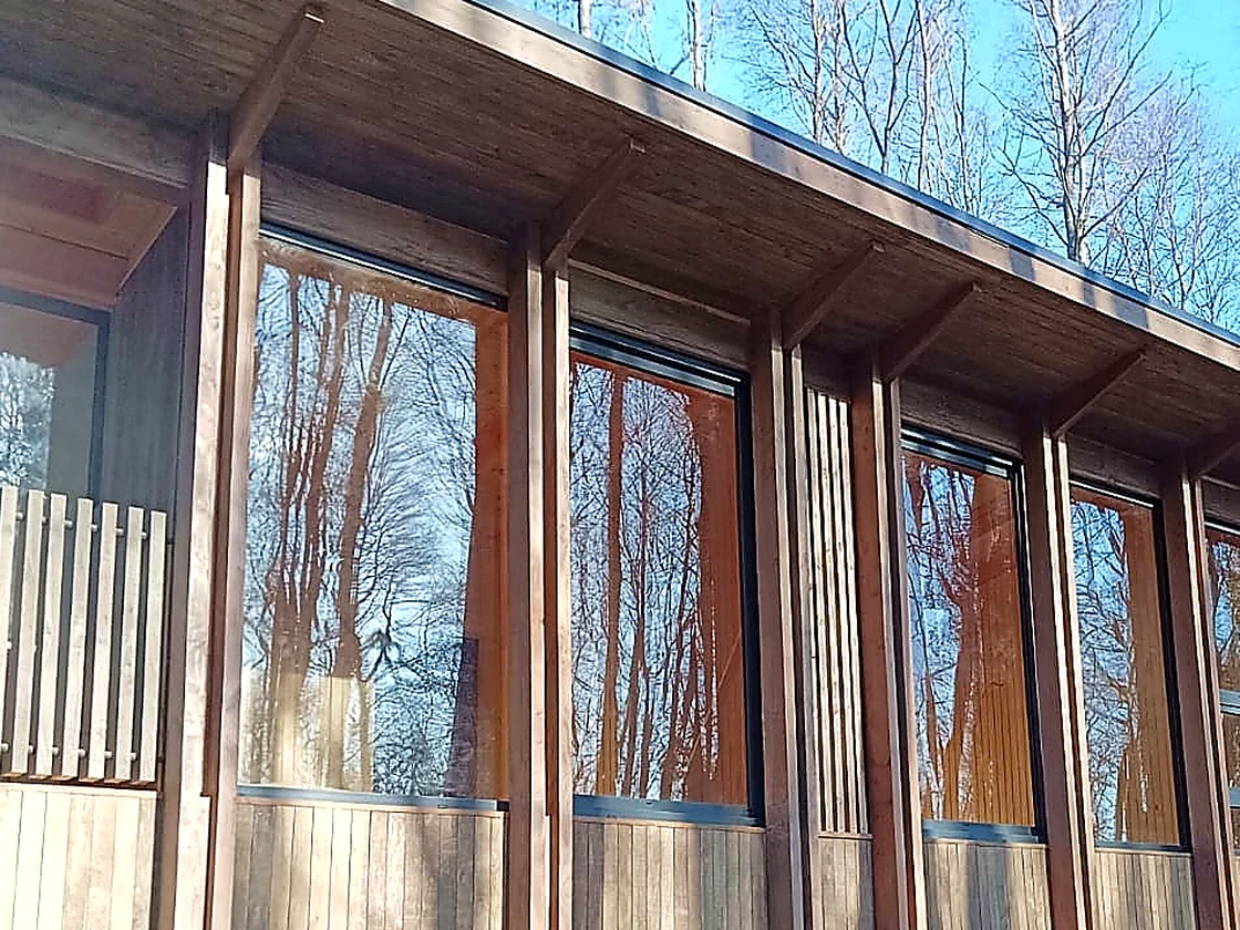Fachada de vivienda con estructura de madera, paños vidriados y modulación vertical