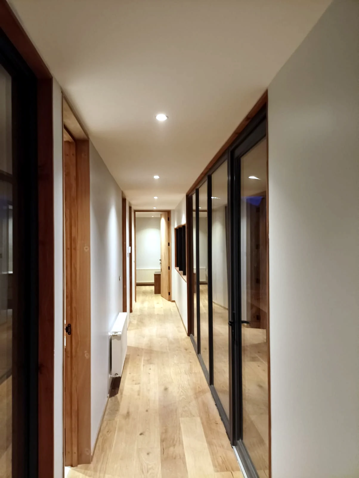 Pasillo interior terminado con puertas de madera y cerramientos acristalados