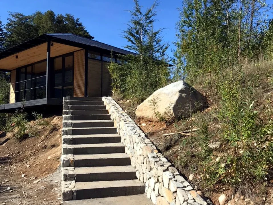 Escalera exterior y muro de contención en piedra como acceso peatonal a una vivienda